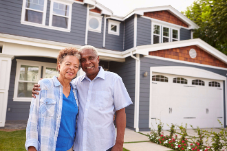 A couple in front of their home.