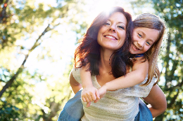 A woman giving her daughter a piggy back ride.