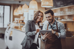 A business owner in his store and a banker are viewing information on a tablet.