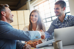 A man and woman shaking hands with their banker.