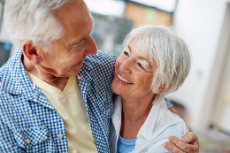 An elderly couple smiling at each other.