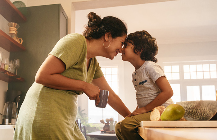 Mother and son nuzzling in the kitchen.