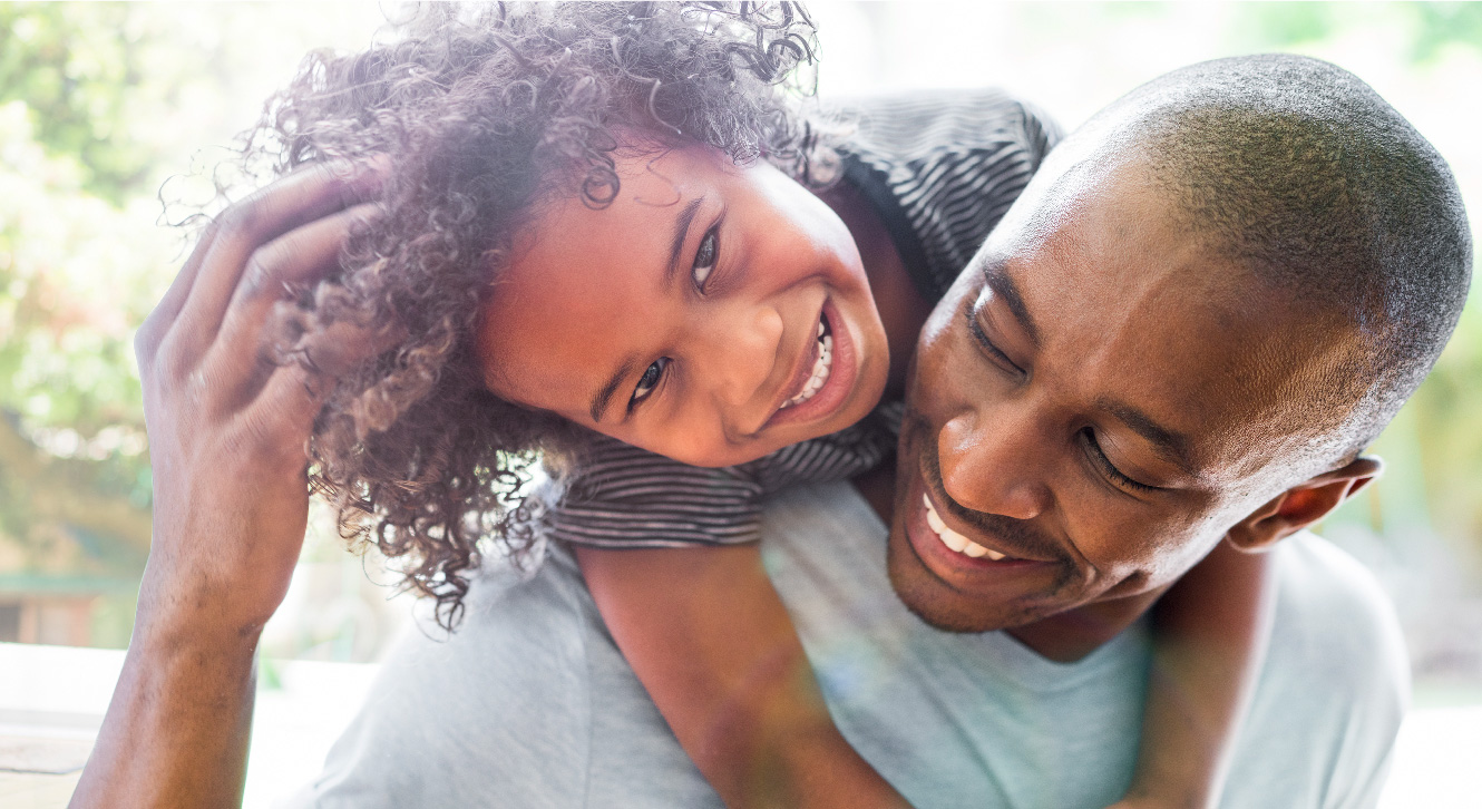 A man smiling with his son around his shoulders