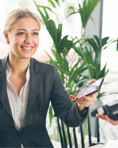 Image of a young woman using her smartphone to pay for a transaction.