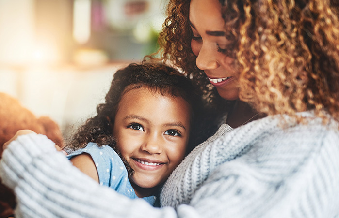Mother holding daughter smiling.