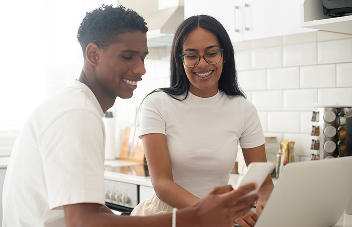 Couple in their kitchen looking at their laptop.